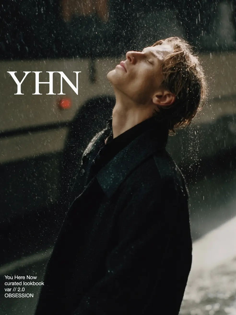 SS26 lookbook, Obsession: a man looking up into the rain beside a bus, with YHN lettering