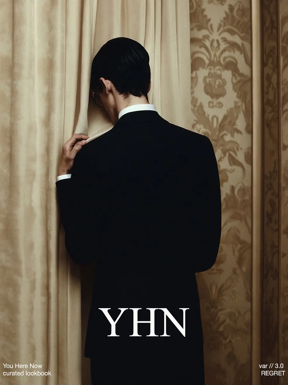 SS26 lookbook, Regret: a man in a black suit facing a gold curtain, his back to the camera, with YHN lettering
